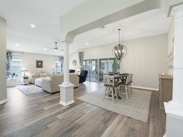 living room with ornate columns, light hardwood / wood-style floors, a healthy amount of sunlight, and ceiling fan with notable chandelier