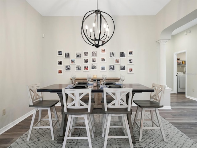 dining area featuring dark hardwood / wood-style flooring, washer / clothes dryer, a notable chandelier, and ornate columns