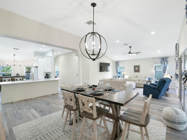 dining space with ceiling fan, light hardwood / wood-style flooring, lofted ceiling, and decorative columns