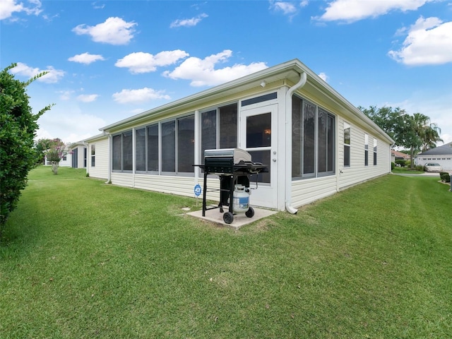 rear view of house featuring a sunroom and a yard