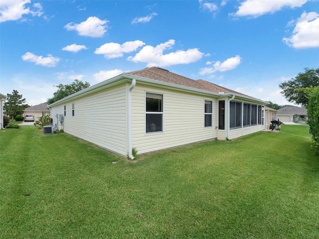 view of side of home featuring a sunroom, a yard, and cooling unit