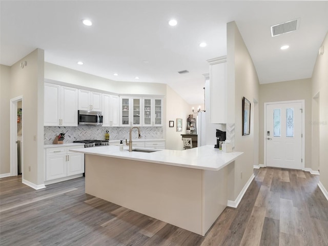 kitchen with kitchen peninsula, sink, light hardwood / wood-style floors, and white cabinets