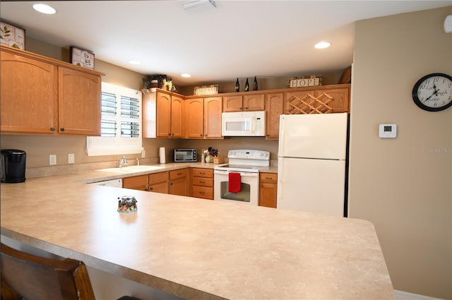 kitchen with kitchen peninsula, white appliances, built in desk, and sink