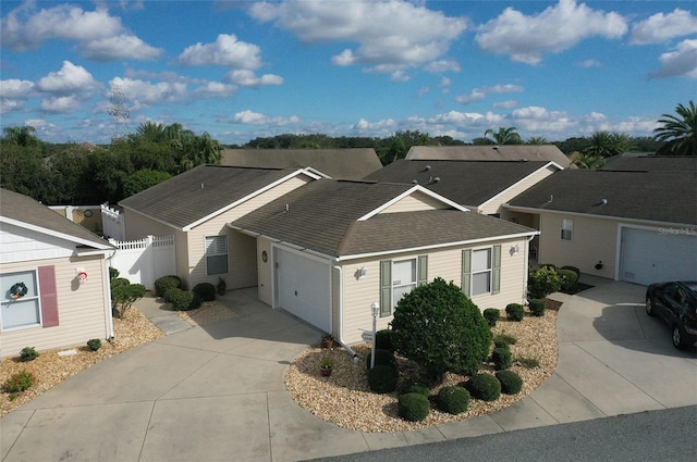 single story home featuring a garage, a residential view, concrete driveway, and roof with shingles