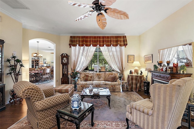 living room with ceiling fan with notable chandelier, crown molding, and dark hardwood / wood-style flooring