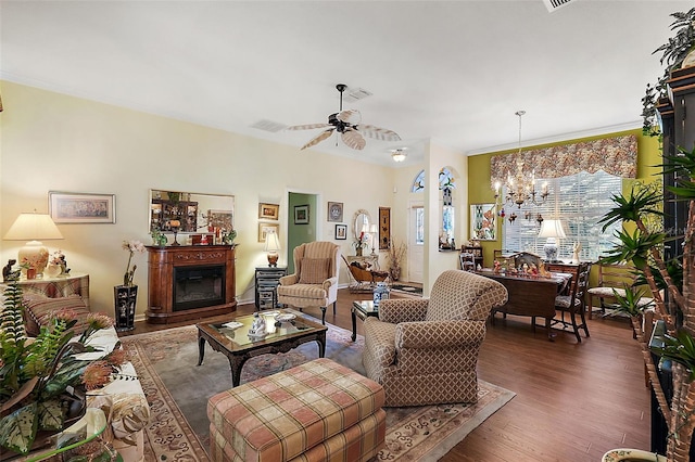 living room with ceiling fan with notable chandelier, crown molding, and dark hardwood / wood-style flooring