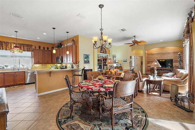 tiled dining room with ceiling fan with notable chandelier