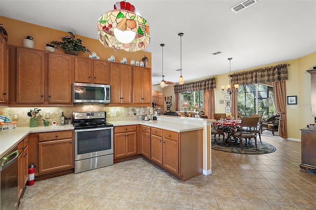 kitchen with stainless steel appliances, kitchen peninsula, light tile patterned flooring, backsplash, and decorative light fixtures