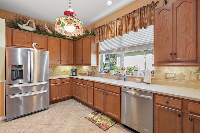 kitchen with stainless steel appliances, light tile patterned floors, hanging light fixtures, decorative backsplash, and sink