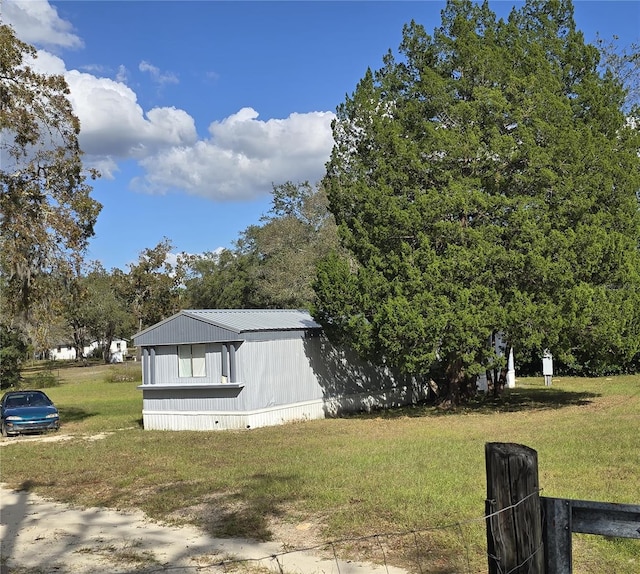 view of property exterior featuring metal roof and a lawn