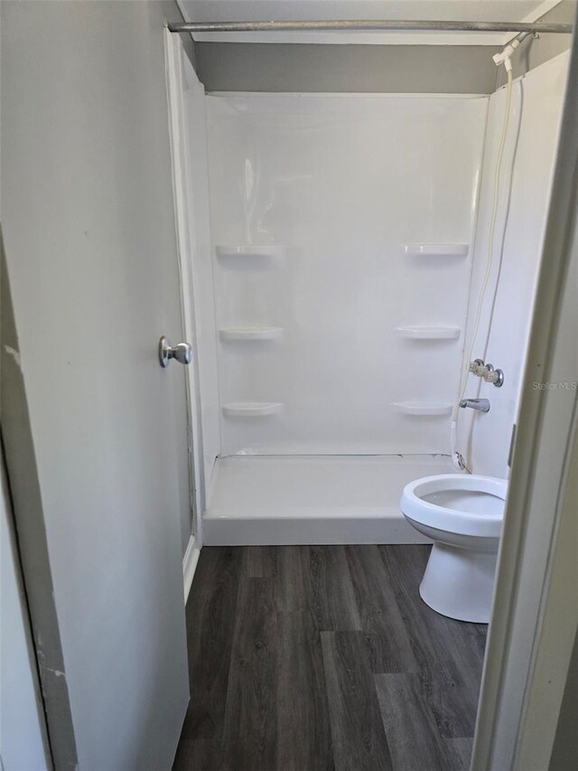 bathroom featuring a shower stall, toilet, and wood finished floors