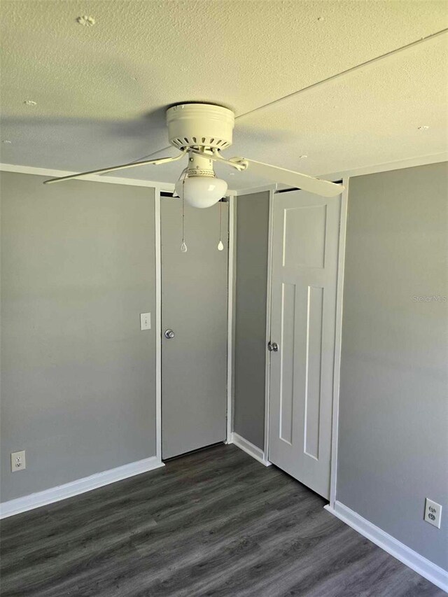 unfurnished room with a ceiling fan, dark wood finished floors, a textured ceiling, and baseboards