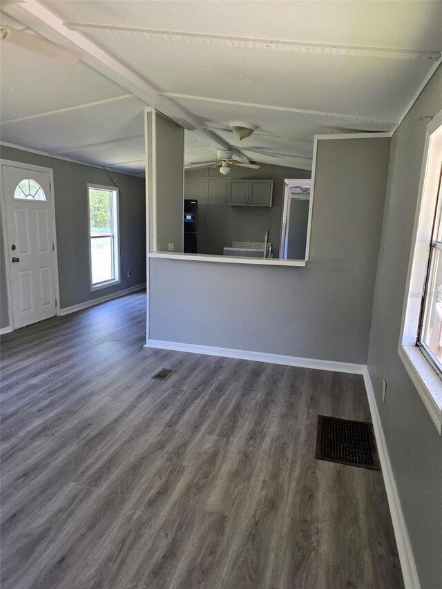 interior space with dark wood-style floors, visible vents, lofted ceiling with beams, and baseboards