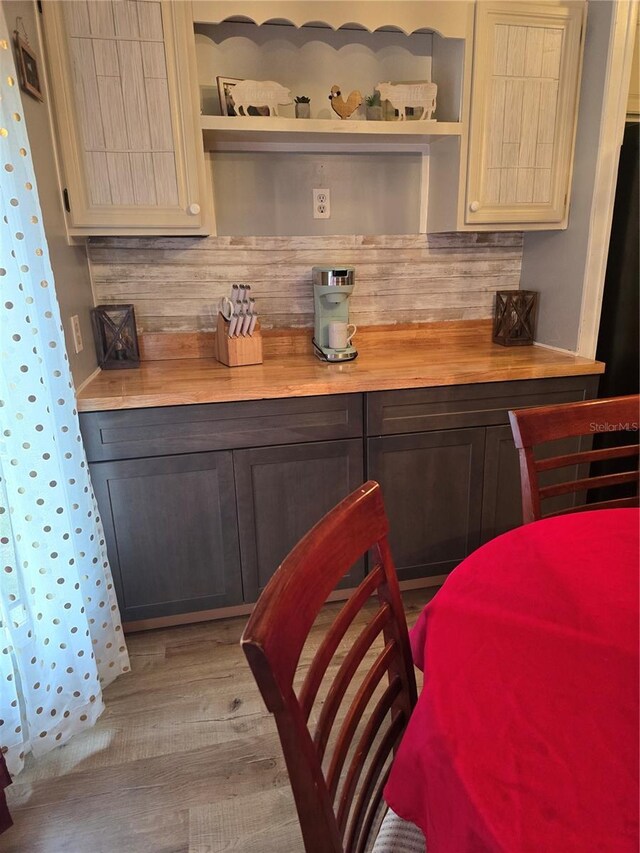 bar featuring light wood finished floors, a dry bar, and tasteful backsplash