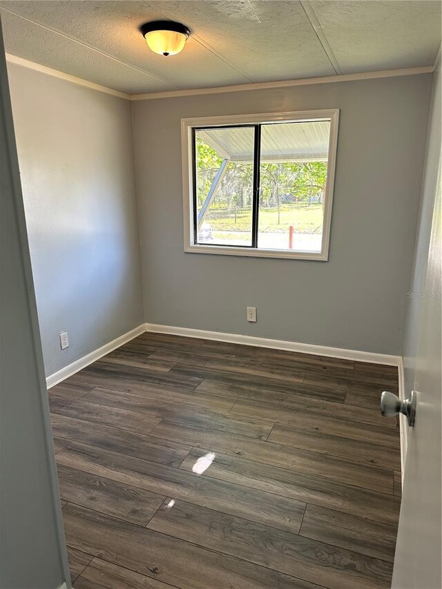 unfurnished room with baseboards, dark wood-style flooring, a textured ceiling, and crown molding