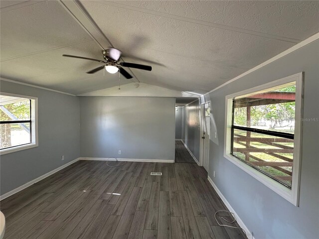 unfurnished room featuring baseboards, dark wood finished floors, vaulted ceiling, crown molding, and a textured ceiling