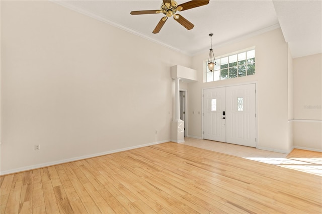 foyer with a towering ceiling, light hardwood / wood-style flooring, ceiling fan, and crown molding