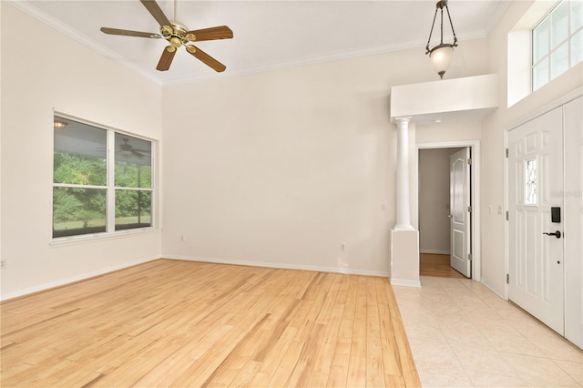 foyer entrance with ornamental molding, light wood-type flooring, plenty of natural light, and decorative columns