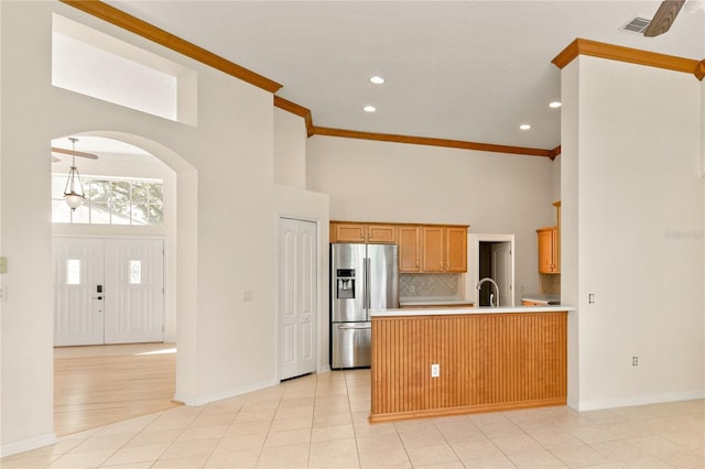 kitchen with ornamental molding, kitchen peninsula, sink, and stainless steel fridge with ice dispenser