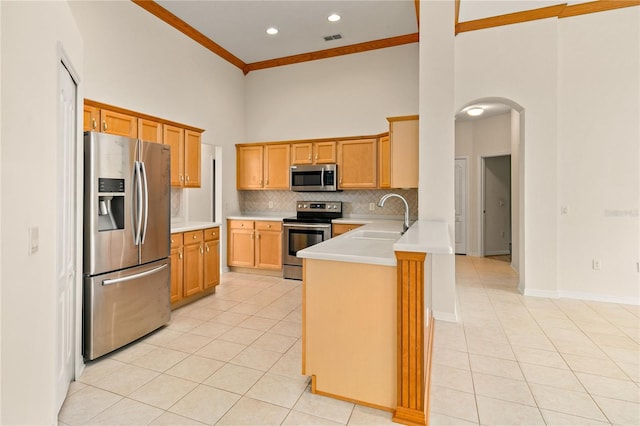 kitchen featuring sink, kitchen peninsula, appliances with stainless steel finishes, light tile patterned floors, and crown molding