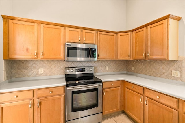 kitchen with decorative backsplash, light tile patterned floors, and stainless steel appliances