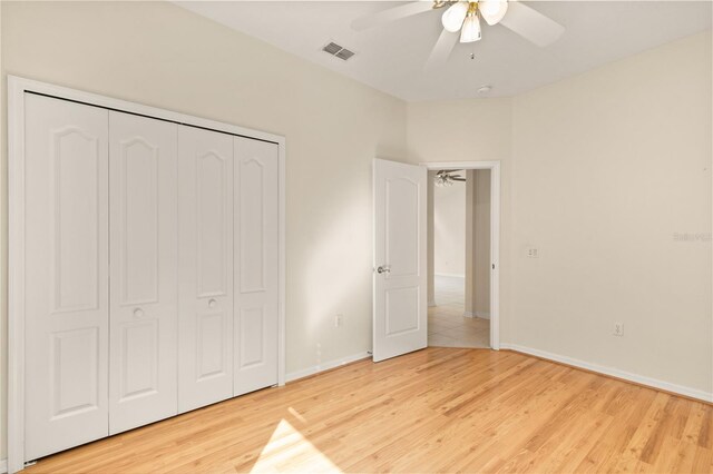 unfurnished bedroom with light hardwood / wood-style floors, ceiling fan, and a closet