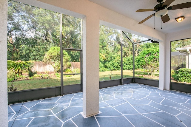 unfurnished sunroom featuring ceiling fan and plenty of natural light