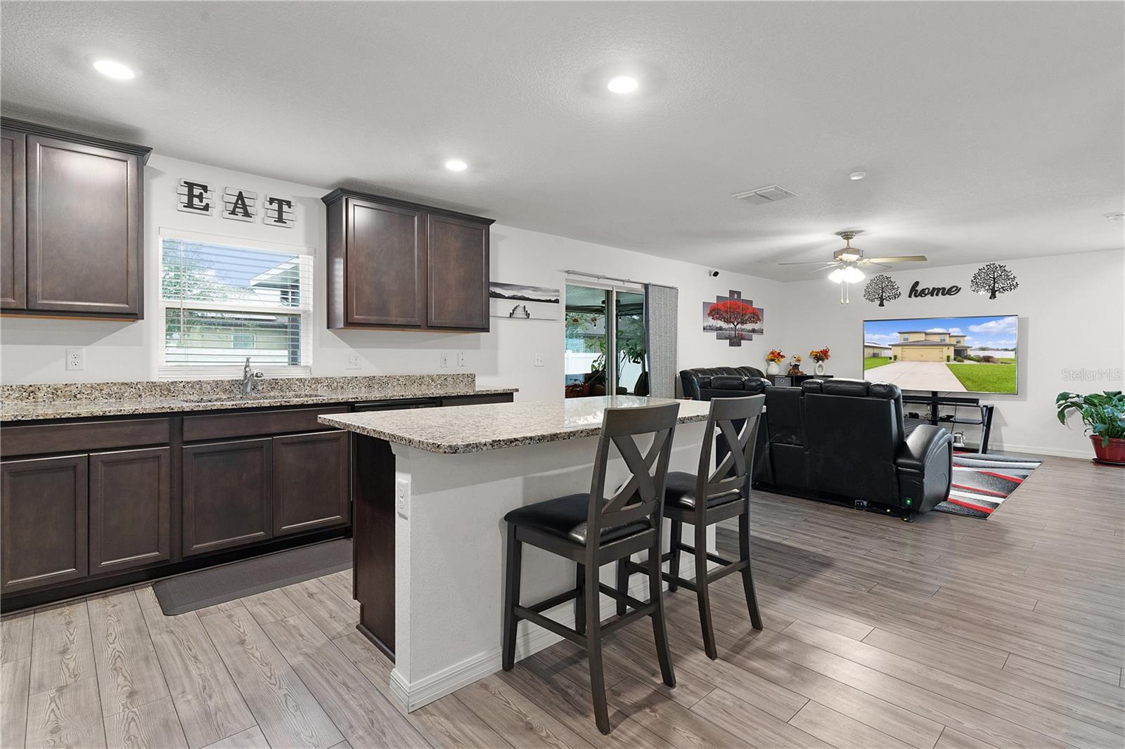 kitchen with light stone countertops, light wood-type flooring, a healthy amount of sunlight, sink, and a kitchen island