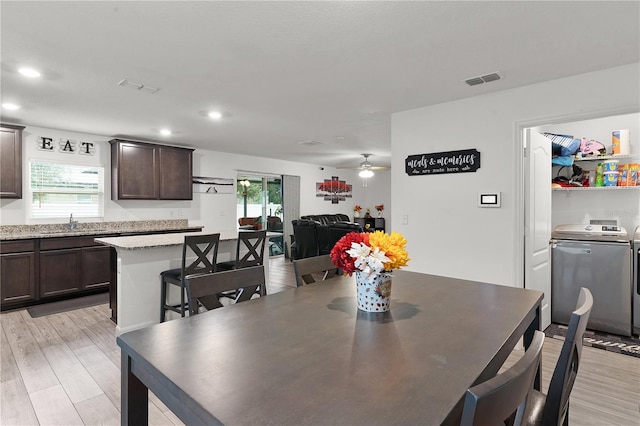 dining area with ceiling fan, light hardwood / wood-style floors, separate washer and dryer, and sink