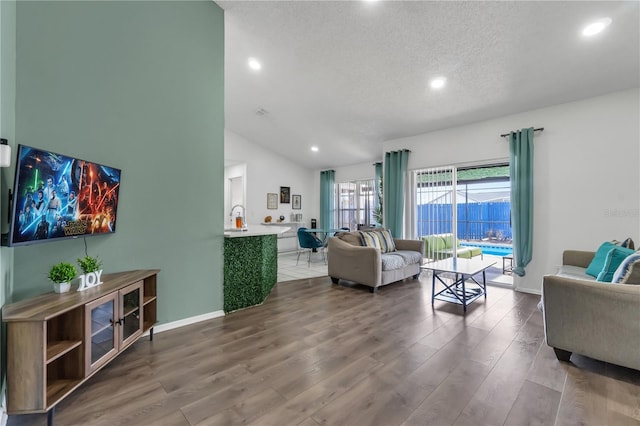 living room with hardwood / wood-style flooring, a textured ceiling, and lofted ceiling