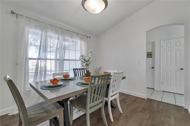 dining space with vaulted ceiling and dark hardwood / wood-style floors