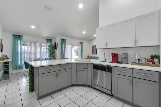 kitchen featuring stainless steel dishwasher, sink, kitchen peninsula, light tile patterned floors, and gray cabinetry