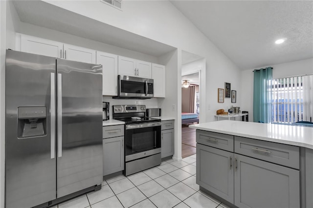 kitchen with vaulted ceiling, light tile patterned floors, gray cabinetry, white cabinets, and stainless steel appliances