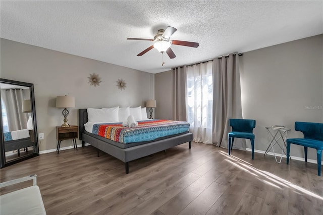 bedroom with ceiling fan, dark wood-type flooring, and a textured ceiling