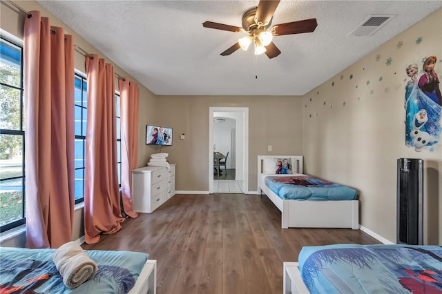 bedroom featuring ceiling fan, hardwood / wood-style floors, a textured ceiling, and multiple windows