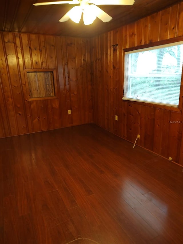 spare room with hardwood / wood-style flooring, ceiling fan, and wooden walls