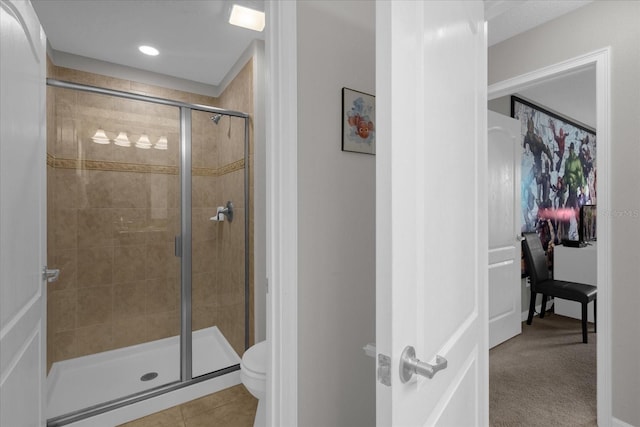 bathroom featuring a stall shower, toilet, and tile patterned floors