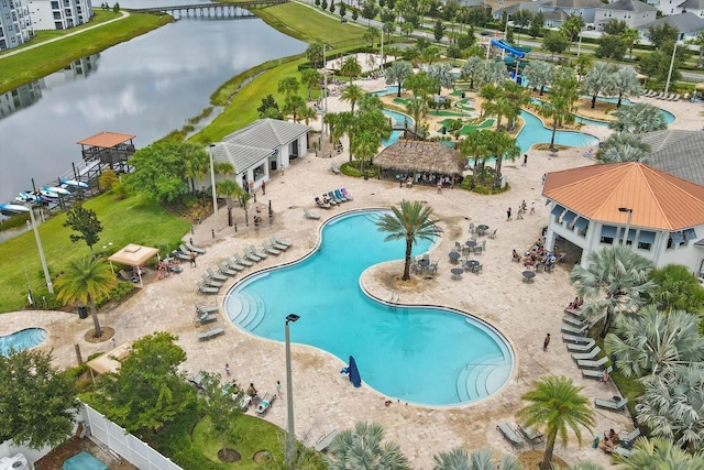 pool with a water view, a water slide, and a patio