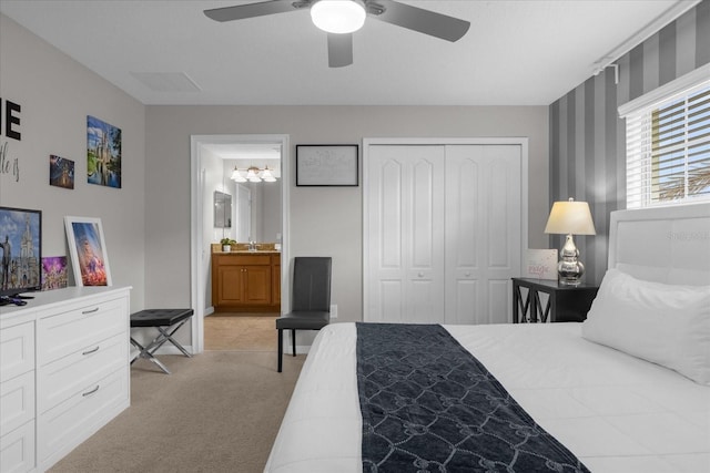 bedroom with a closet, a ceiling fan, light colored carpet, ensuite bathroom, and a sink