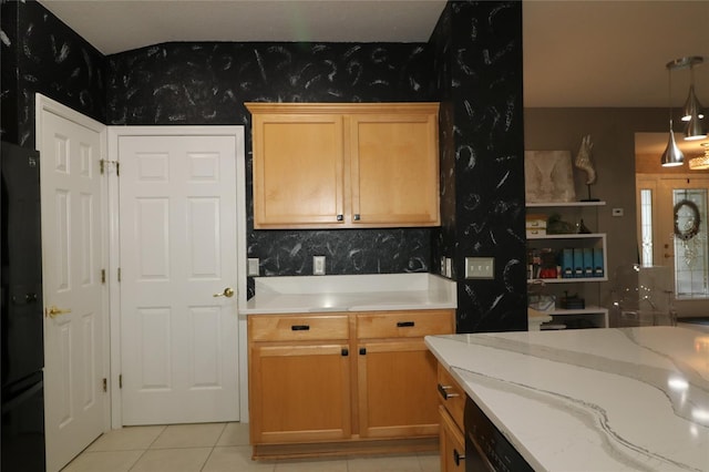 kitchen featuring black refrigerator, light stone counters, light tile patterned floors, light brown cabinets, and pendant lighting