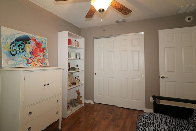 bedroom with ceiling fan, a closet, dark wood-type flooring, and a textured ceiling