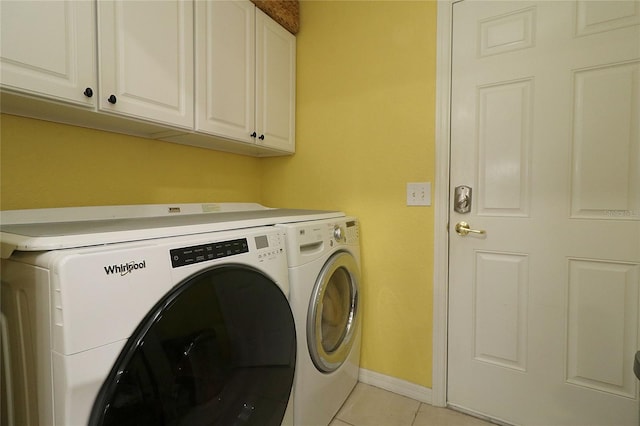 laundry area featuring cabinets, light tile patterned floors, and washer and dryer