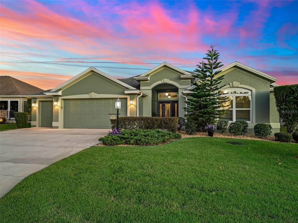 ranch-style home featuring a garage and a lawn