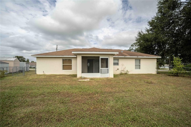 rear view of property with a lawn and a sunroom