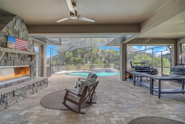 view of patio with an outdoor stone fireplace, ceiling fan, and a grill