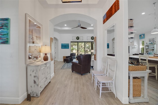 hall with a tray ceiling and light hardwood / wood-style flooring