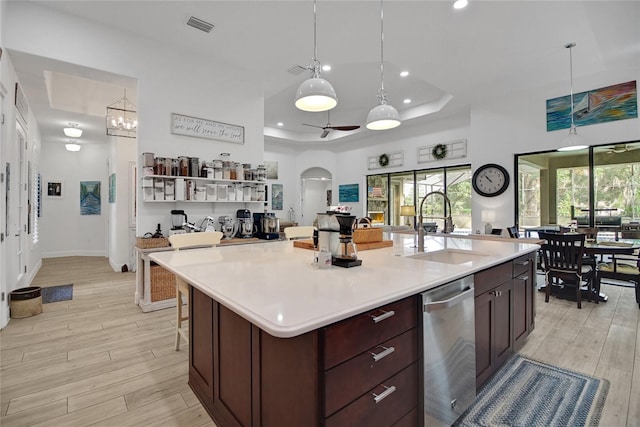 kitchen featuring light wood-type flooring, ceiling fan with notable chandelier, sink, dishwasher, and hanging light fixtures