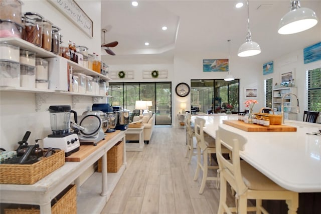 kitchen featuring a wealth of natural light, ceiling fan, light hardwood / wood-style floors, and decorative light fixtures