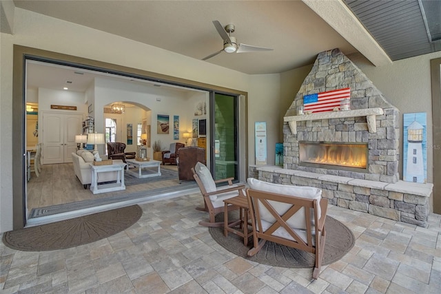 view of patio featuring ceiling fan and a stone fireplace