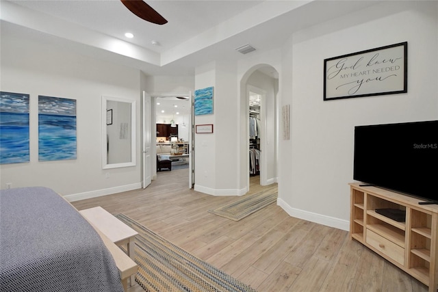 bedroom featuring ceiling fan, a spacious closet, and light wood-type flooring